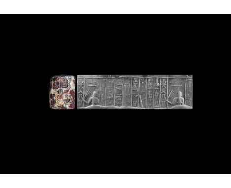 1530-1150 BC. A red-white mottled agate cylinder seal with a cross above a seated(?) person, the right hand holding a barley 