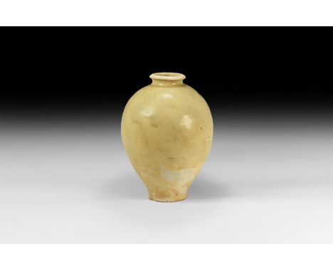 Tang Dynasty, 618-907 AD. A ceramic glazed jar with pale celadon glaze; rolled rim with short neck; bulbous body tapering to 