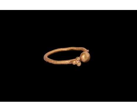3rd-4th century AD. A gold finger ring with coiled texture to the round-section hoop, flat plaque with cluster of three small