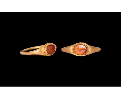 1st century AD. A gold finger ring comprising a slender hoop with flared shoulders, stepped bezel with cell, inset carnelian 