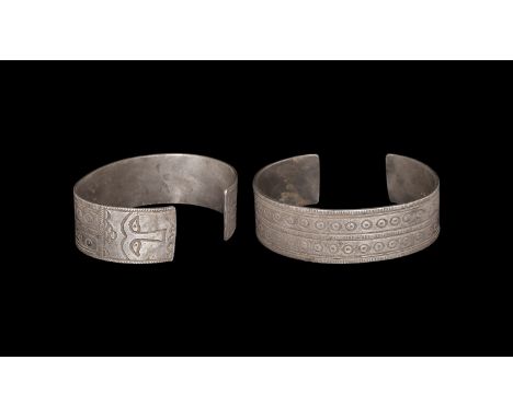 9th-11th century AD. A flat-section silver penannular bracelet with bands of stamped decoration, facing masks to the finials.