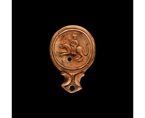 1st century AD. A ceramic oil lamp with flared nozzle, volutes to the side; dished to the top with image of the goddess Cybel