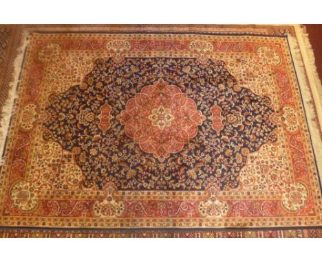 A Keshan style rug, with a ruby medallion on a midnight blue ground within stylised border, L.230cm W.160cm 