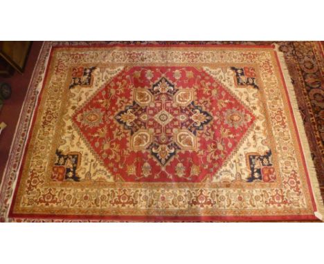 A Heriz style carpet, the central medallion on a ruby ground within a wide stylised ivory border, L.280cm W.200cm 