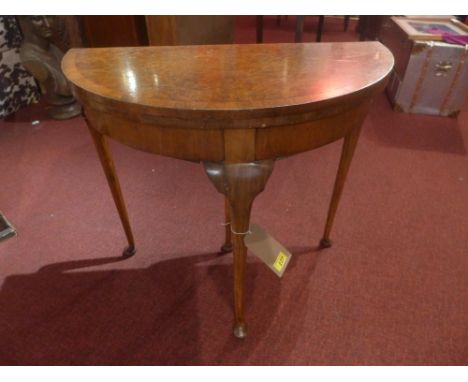 A Queen Anne style walnut demi-lune card table, with green baize surface raised on cabriole supports 