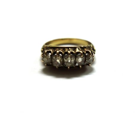 A gold and five-stone diamond ring, the graduated cushion shaped old-cut stones claw-set between scroll carved shoulders, un-