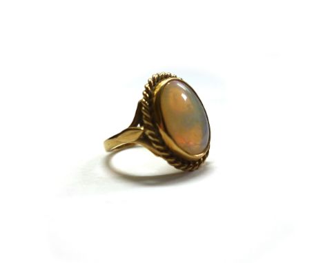 A modern 18ct gold and opal ring, the cabochon white opal rub-over set within a rope-twist surround, between fleurs de lys sh