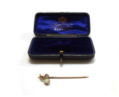 An early 20th century gold, white opal and diamond stick pin, rub-over set with an oval cabochon white opal and an old cut di