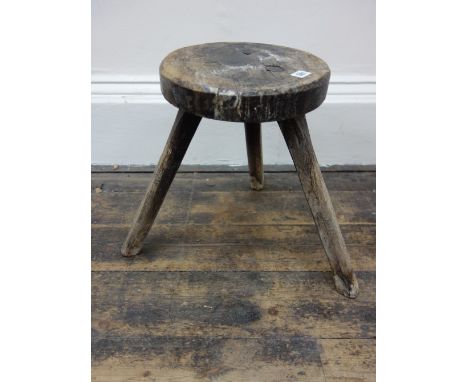 An elm stool, first half 19th century, the circular seat, on three splayed chamfered legs, 31cm diameter.