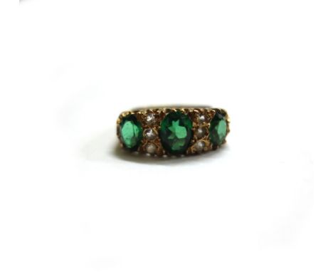 A 9ct gold, green and white stone ring, the three graduated oval faceted green spinels divided by white spinel three stone sp