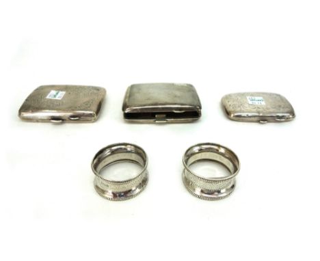 A pair of silver napkin rings, Birmingham 1917, engine turned and beaded and three silver cigarette cases, various dates, mak