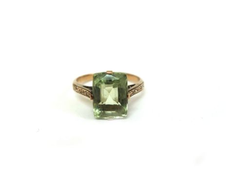 A green single stone gem set ring, the rectangular mixed-cut stone claw-set in yellow gold, engraved shoulders, unmarked, 3.2