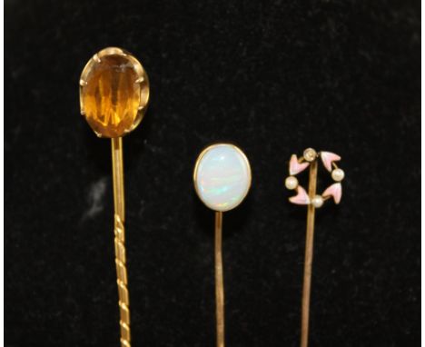 A yellow metal tie pin, claw set with an oval citrine, together with a similar opal set pin and an emamel and pearl set pin. 