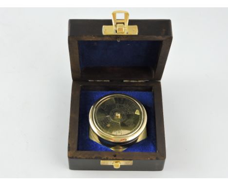 A brass compass, the lid incorporating a calendar, within a hardwood box, W. 9cm.