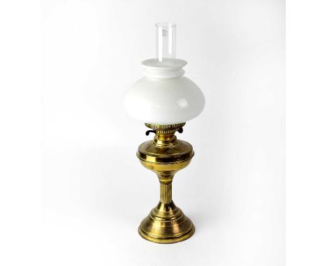 A brass oil lamp with opaque shade and chimney, height 55cm.