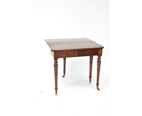 An early 20th century mahogany fold-over tea table raised on turned tapering supports to brass caps and ceramic castors, 75 x