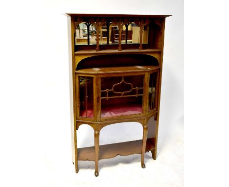 An Arts &amp; Crafts mahogany side cabinet, the upper section with open shelf and bevel edged mirror, with fret carved floral