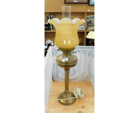 A brass oil lamp, with an amber colour glass shade and glass chimney, converted to electricity, 70cm high.&nbsp;
Buyer Note: 