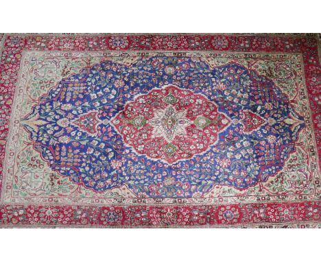 A 20th century Kashan carpet with central floral medallion, on a red and blue ground, contained by floral motifs and borders,