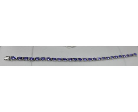 A boxed 18ct white gold diamond and tanzanite tennis bracelet composed of alternating stones to a secure clasp, L: 18.5cm, 8.