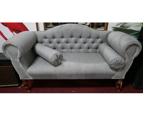 A contemporary camel back sofa, buttoned grey upholstery, raised on turned legs and castors, H.71 W.135 D.55cm 