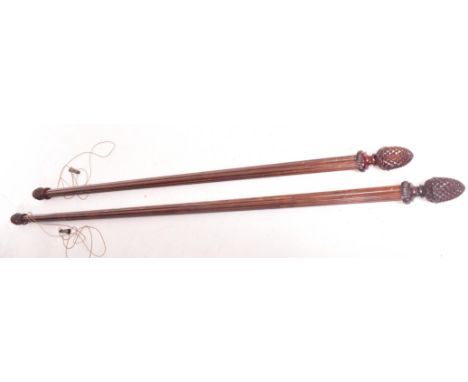 A pair of vintage 20th century curtain poles. Solid wood pineapple finials, with shaped brass effect metal fixings. Two diffe