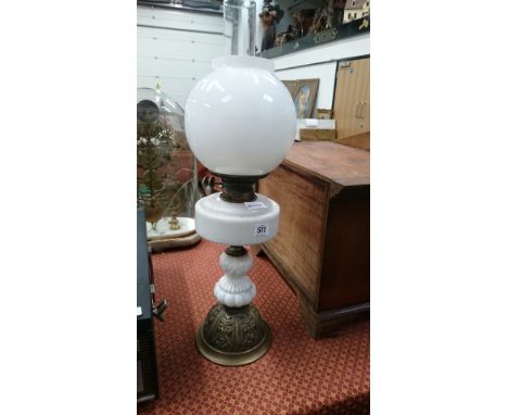 An opaque glass oil lamp on embossed brass base with opaque white glass shade and funnel.