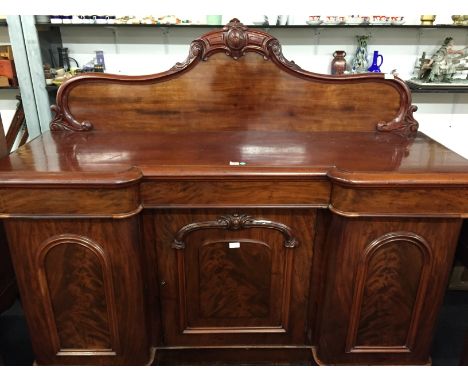 A very large flame mahogany breakfront sideboard with decorative carved back rail, three drawers and three doors below, centr