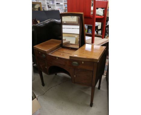 George III Mahogany bow front enclosed Dressing Table, the central hinged lid enclosing a ratchet adjustable mirror and three