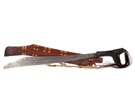 INDONESIAN PARANG EARLY 20TH CENTURY the curved steel blade over a carved hardwood grip mounted with hair, in original carved