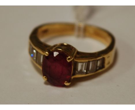 A modern ladies 18ct gold oval cut ruby dress ring, the shoulders each set with three graduated baguette cut diamonds