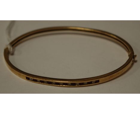 A 10ct gold ruby and diamond channel set hinged bangle