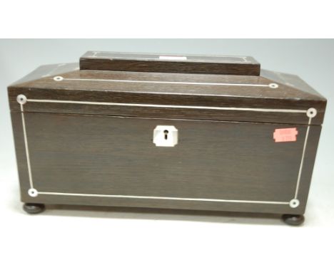 A circa 1830 mahogany and mother of pearl inlaid tea caddy of sarcophagus form, having ring handles and on turned bun feet