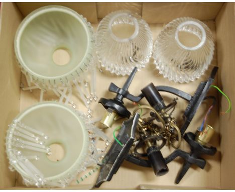 A pair of wrought iron wall light fittings, together with two pairs of glass shades (3)