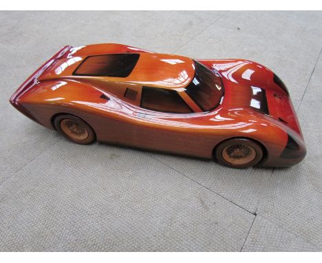 A carved wooden sports car by Woodley Productions, signed to the underside by artist Curtis Stimpson No. 84/450