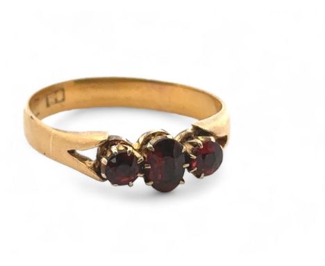 A three stone garnet ring, size O. Hallmarks rubbed and unclear but tested as using XRF as 18ct gold. Weight 3.71g. Shank mis