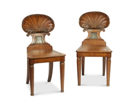 A pair of Regency carved oak shell-back hall chairs attributed to Gillows The backs painted with family crests, above rectang