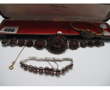 A Garnet Set Bangle, claw set; a garnet set bracelet, graduated set, a graduated panel bracelet, hinged to snap clasp. (3)