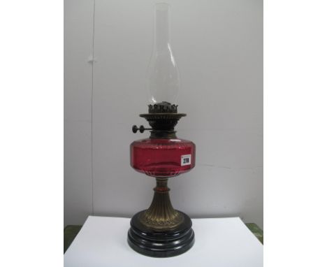 A XIX Century Oil Lamp, with a glass funnel, cranberry glass well, brass pedestal, black base.