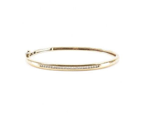 A hallmarked 9ct yellow gold &amp; diamond bangle bracelet. The hinged bangle having a centred row of channel set round cut d