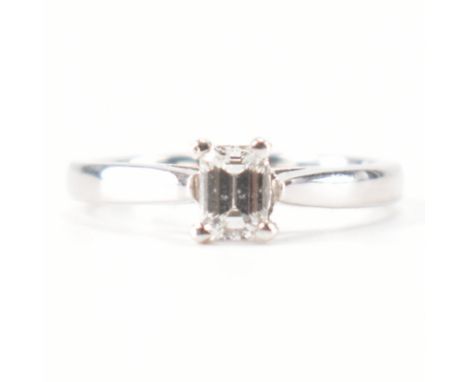 A hallmarked 18ct white gold &amp; diamond solitaire engagement style ring. The ring having an emerald cut prong basket set d