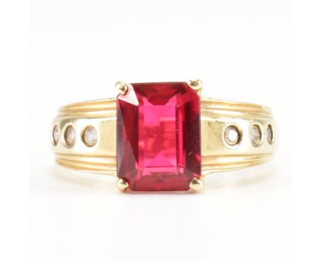 A hallmarked 14ct gold synthetic ruby and white stone dress ring. The ring being set with a emerald cut ruby with six white s