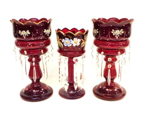 A pair of Victorian ruby tinted glass table lustres, each decorated with raised enamels with flowers and leaves etc. on a dom