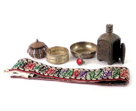 A group of eastern wares, comprising a hammered bangle, a brass coin centred bowl, a brass storage jar, white metal paste sto