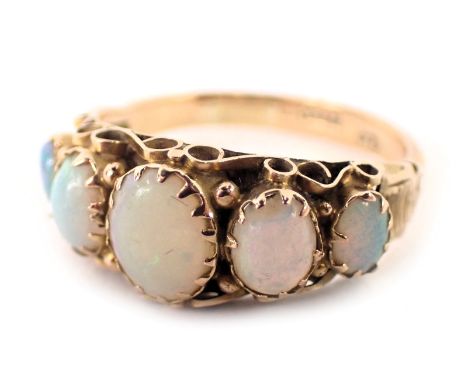 A 9ct gold opal dress ring, the ring head set with five oval opals in rub over and claw setting, with etched shoulders, ring 