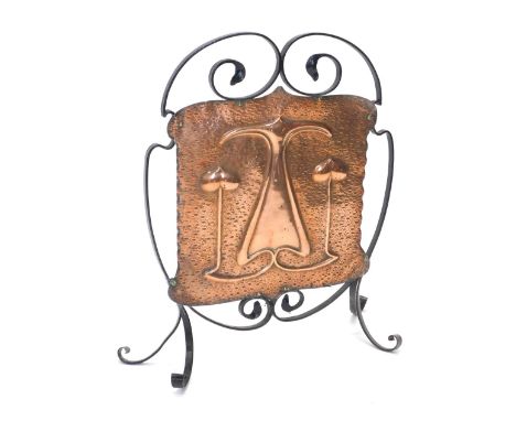 A late 19th/early 20thC wrought iron Art Nouveau fire screen, inset with a hammered copper banner, 68cm high, 56cm wide. 