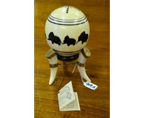 An ostrich egg painted with elephants by Carol Smit-Eggart, 1993, on pig-tooth tripod stand 