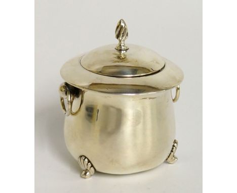 A two handled cauldron shaped caddy the domed cover with flambeau finial, pair of ring handles on three rudimentary feet, 9.5