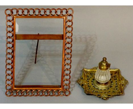 A copper frame of interlaced circles, 31cm x 23cm overall, glazed; a Victorian brass inkwell the rectangular base pierced wit