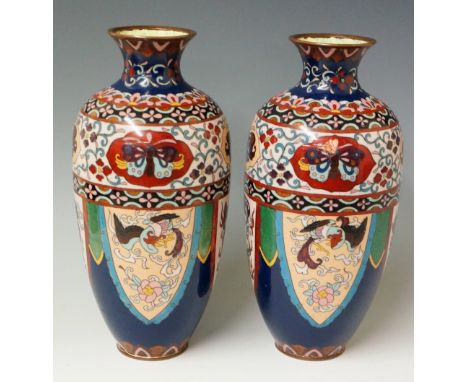 A pair of Japanese cloisonné enamel vases of urnular shape with everted necks the panelled bodies decorated with stylised pho